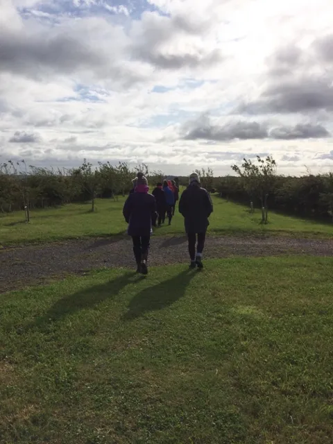 Retreat guests walking along a grassy track through open farmland