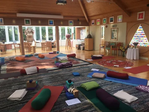 A bright yoga room laid out with mats, bolsters and blankets