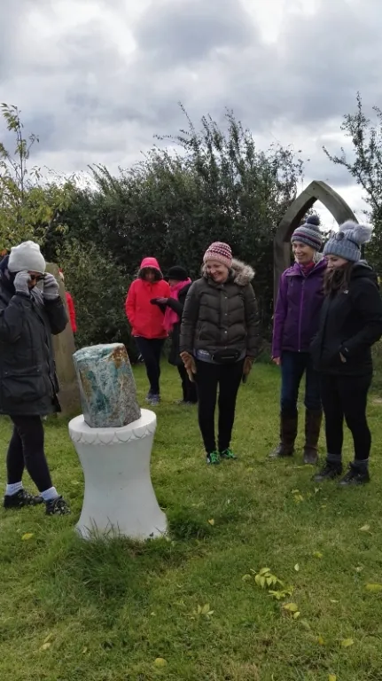 Retreat guests in warm coats gathered outdoors beside a stone on a plinth